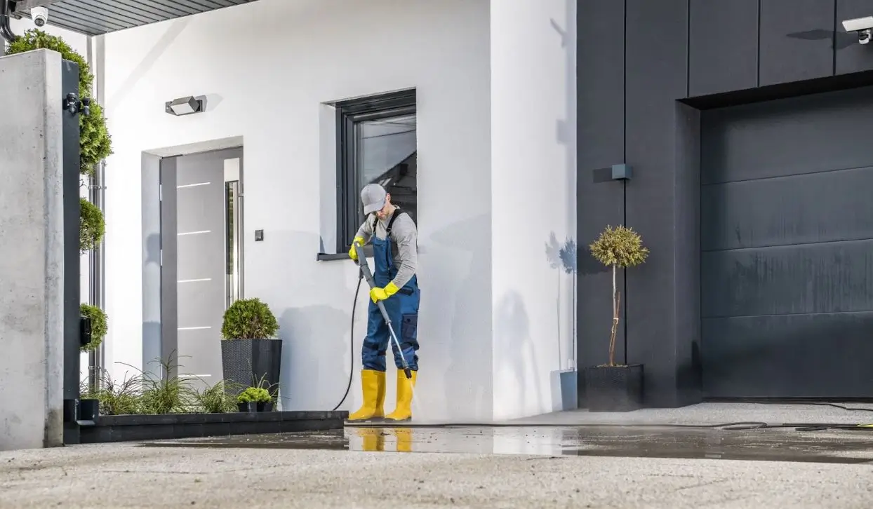 Man pressure washing a home.