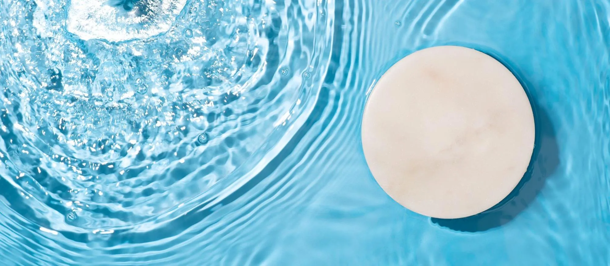 A close-up of pool water with a cleaning tablet.