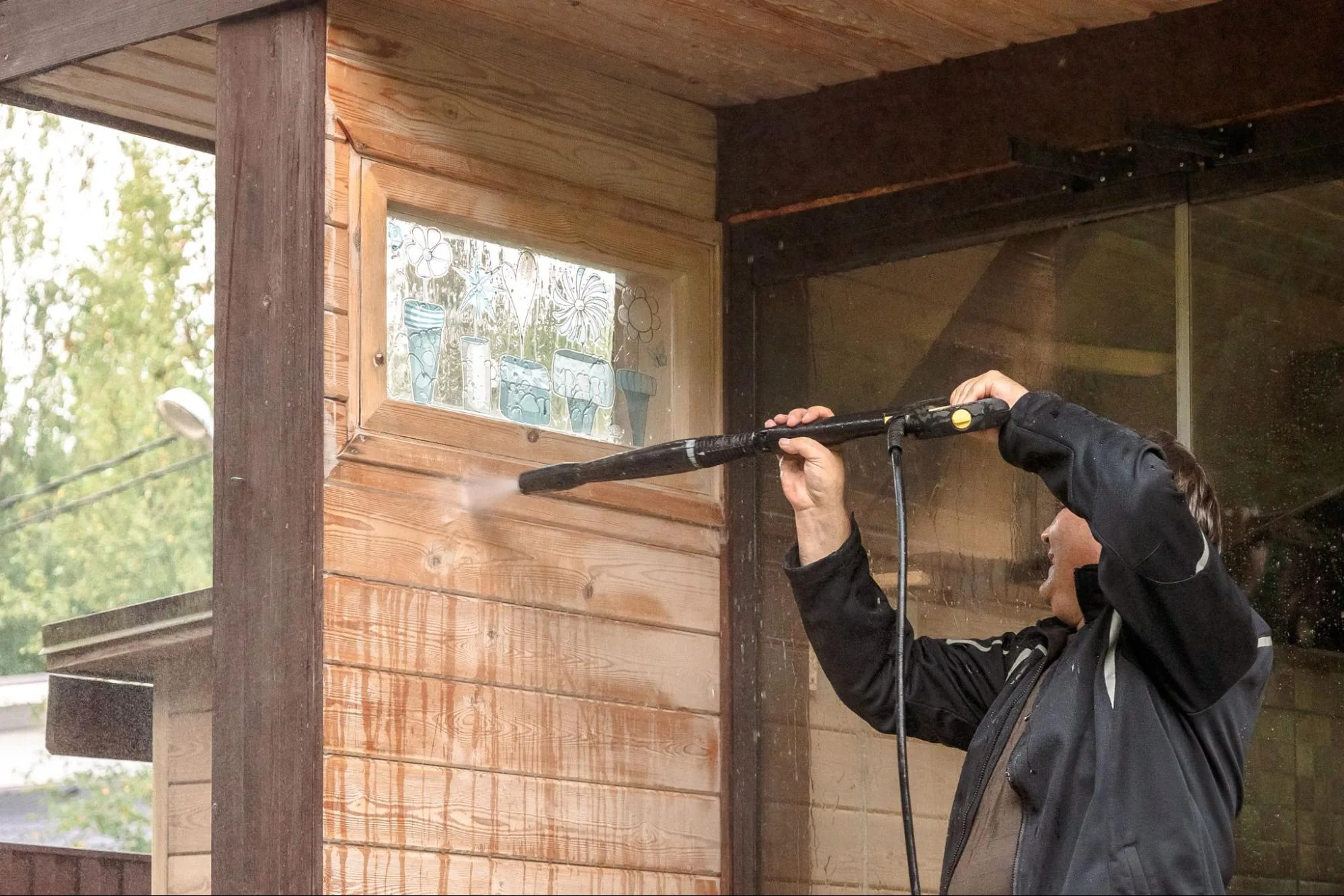 A DIYer cleans his front stairs with a pressure washer.
