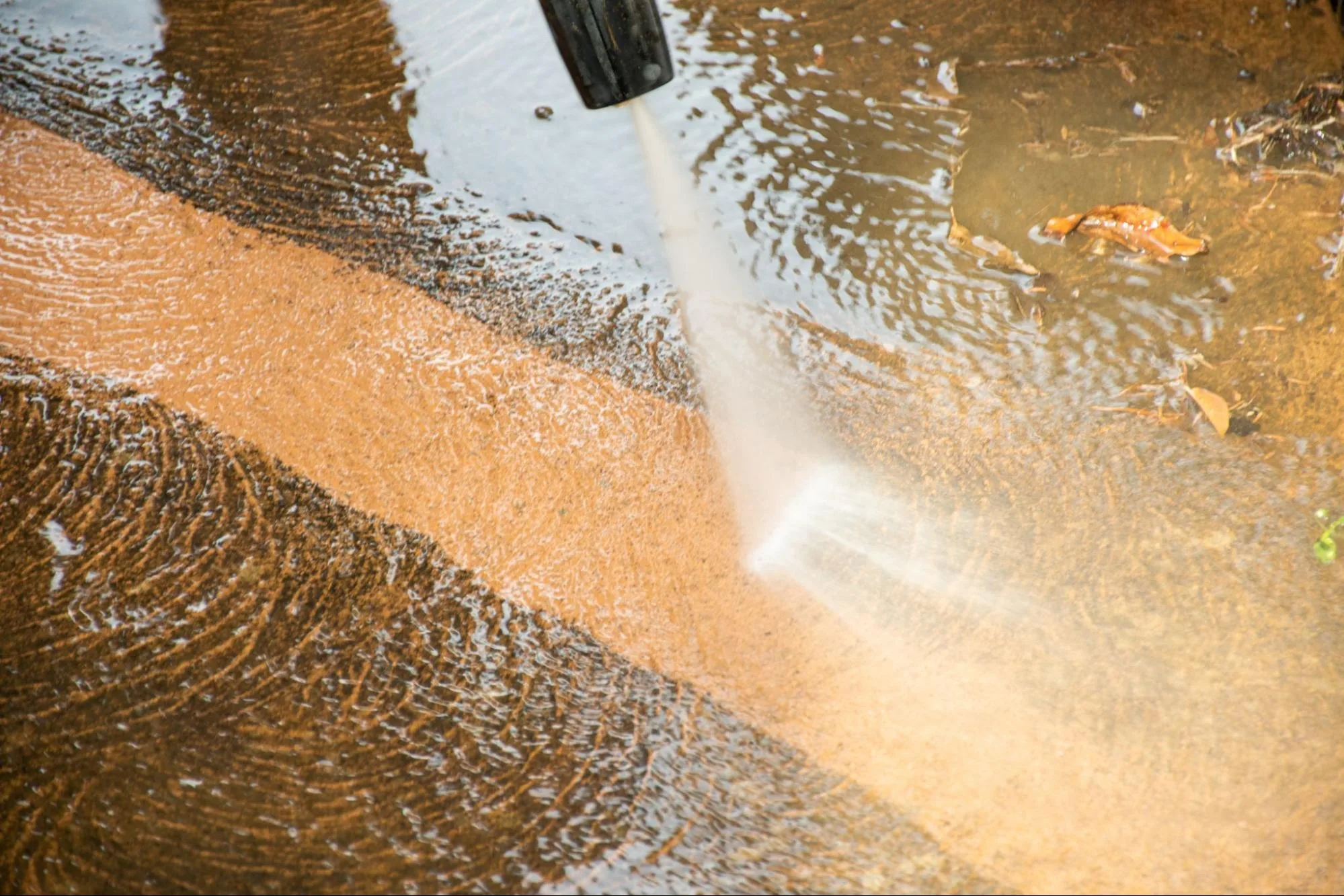 Detailed view of an industrial pressure washer blasting dirt off an industrial concrete floor